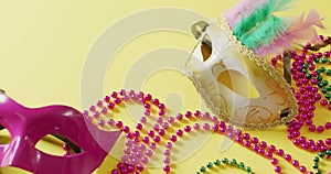 Video of two masquerade masks and carnival mardi gras beads on yellow background with copy space