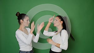 Video of two young woman dancing  toward camera, isolated on green