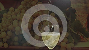 Video of white wine pouring into glass with grapes background