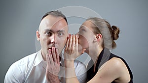 Video of woman talking secret on grey background