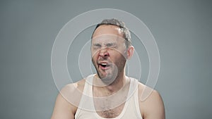 Video of yawning bristly man on gray background