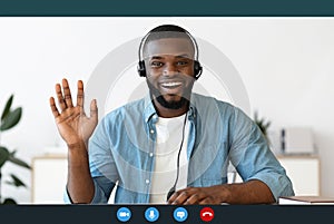 Videocall screenshot of happy young black man in headset having web conference photo