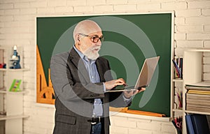 Videoconferencing keeps homebound students connected. Senior intelligent man teacher use laptop. Distant education goals photo