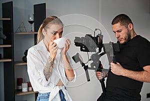 Videographer man shooting footage with female model, using camera.