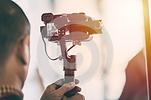 Videographer recording video with mirrorless digital camera on Gimbal photo