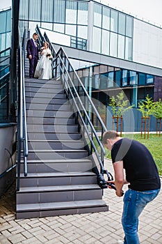 Videographer shoots a film with the newlyweds on the stairs