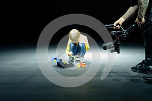 videographer shoots on video camera, as little six year old kid boy painting or colorize or colour model airplane