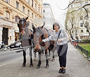 Vienna, Austria. Girl tourist stroking horses in a carriage.