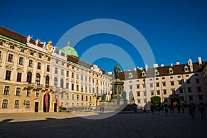 Vienna, Austria: Hofburg palace and panoramic square view, people walking and fiaker with white horses in Vienna, Austria