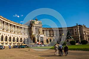 Vienna, Austria: Hofburg palace and panoramic square view, people walking and fiaker with white horses in Vienna, Austria