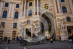 Vienna, Austria: Hofburg palace and panoramic square view, people walking and fiaker with white horses in Vienna, Austria