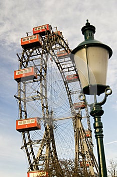 Vienna prater park amusement giant wheel with red cabins. from ground with a blurred street lamp