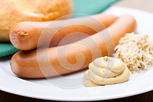 Vienna sausages with a roll, horseradish and mustard on a plate