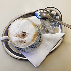 Viennese coffee and a glass of water, on a tray, on a napkin