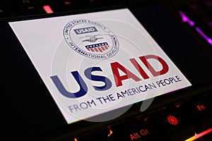 Smartphone screen with logo lettering of USAID government agency on computer keyboard