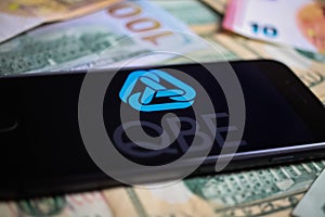 Closeup of smartphone with logo lettering of australian qbe insurance company on paper money currency