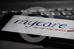 Close up of mobile phone screen on computer keyboard with logo lettering of german online mail-order pharmacy mycare