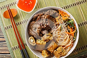 Vietnamese Beef Noodle Salad Bun Bo with crispy nem spring rolls and vegetables closeup. Horizontal top view