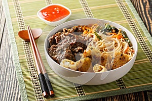 Vietnamese beef noodles salad bun bo xao is filled in fresh herb, savory beef, vegetables and fried spring rolls closeup.