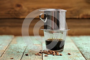 Vietnamese black coffee brewed in French drip filter on turquoise wooden table