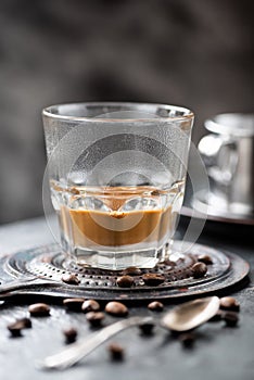 Vietnamese coffee with milk in a glass, coffee beans on a dark background