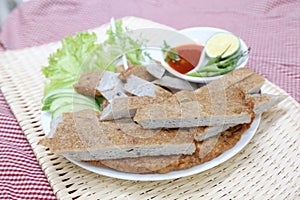 Vietnamese fish paste cake or cha ca on white plate with herbs,