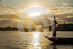 Vietnamese fisherman casts a golden net with a sunset background