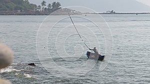 vietnamese fisherman frightens fish in net with stick