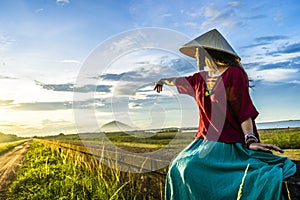 Vietnamese girl sitting on the dike in beautiful sunset with blue sky in Dau Tieng lake, Tay Ninh province, Vietnam