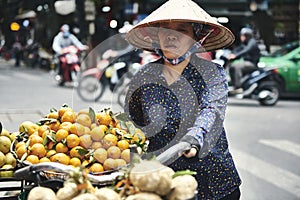 Vietnamese woman with bike selling fruit in the city street