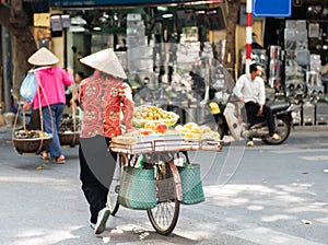 Vietnamese street vendors act and sell their vegetables and fruit products in Hanoi, Vietnam