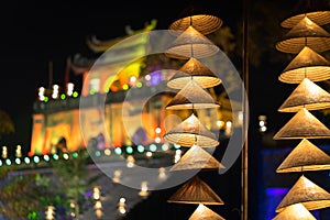 Vietnamese traditional conical hats hanging on wire for decoration with old vintage building on background