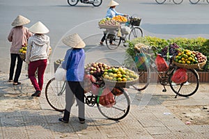 Vietnamese vendors with tropical fruit loaded basket on bike