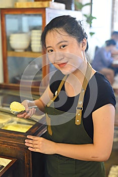 Vietnamese waitress showing a scoop of homemade mango ice cream in cafe