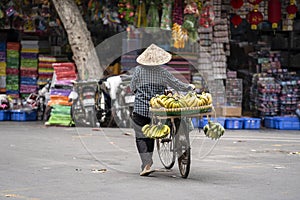 Vietnamese woman with bike selling bananas on the street market of old town in Hanoi, Vietnam