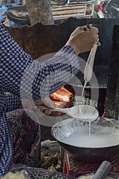 Vietnamese woman makes and sells snacks in a street of Ho Chi Minh City