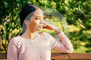 Vietnamese woman in pink sweater sitting on the bench photo