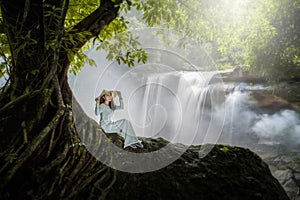 Vietnamese woman sits beneath a beautiful waterfall tree with a