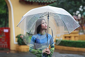 Vietnamese women wear Ao dai holding umbrella in the rain