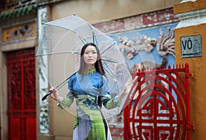 Vietnamese women wear Ao dai holding umbrella in the rain