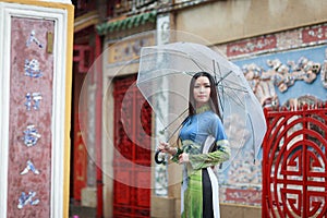 Vietnamese women wear Ao dai holding umbrella in the rain