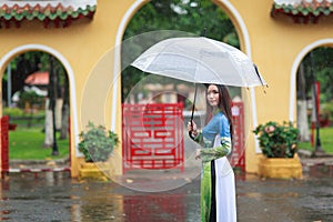 Vietnamese women wear Ao dai holding umbrella in the rain