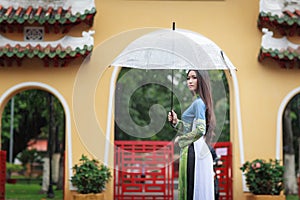 Vietnamese women wear Ao dai holding umbrella in the rain