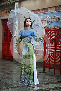 Vietnamese women wear Ao dai holding umbrella in the rain photo