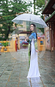 Vietnamese women wear Ao dai holding umbrella in the rain photo