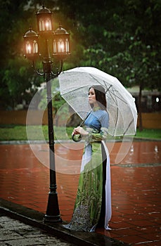 Vietnamese women wear Ao dai holding umbrella in the rain photo