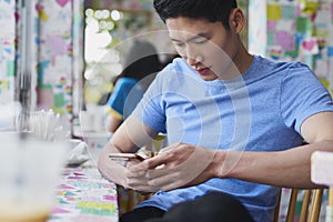 Vietnamese young man using mobile phone in a cafe