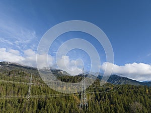 view of 110kV power high-voltage line in the middle of the forest on large metal pylons