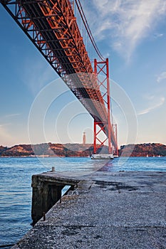 View of 25 de Abril Bridge over Tagus river, Christ the King monument and a quay. Lisbon, Portugal