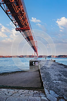 View of 25 de Abril Bridge over Tagus river, Christ the King monument and a quay. Lisbon, Portugal